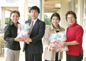 善平教頭(左から2人目)と与那覇教諭(右)にマスコットを贈呈する砂川さん(左)と渡真利さん(右から2人目)=6日、上野小学校